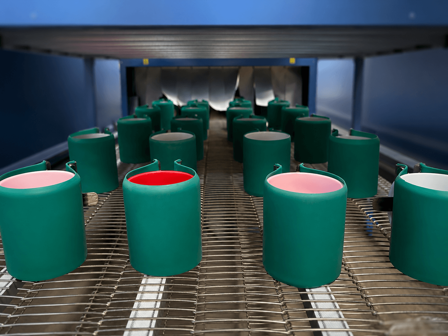 Freshly printed mugs on the production line, cooling before packing